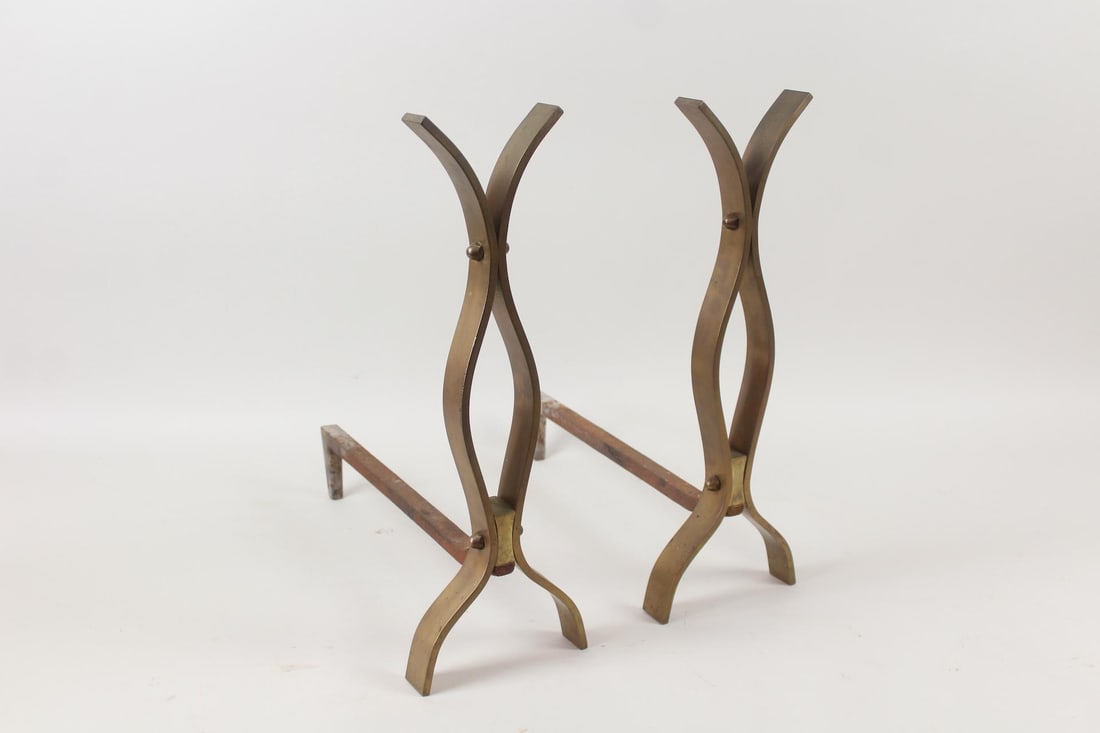 Pair of Mid-Century Modern Sculptural Brass Andirons, Modernist: Pair of Mid-Century Modern Sculptural Brass Andirons. Wonderful pair of andirons have flared brass fronts, with iron supports. Have the style of Donald Deskey but not attributed to. Dimensions are 20