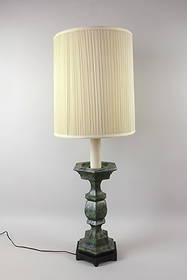 Hollywood Regency Green Metal Table Lamp: Hollywood Regency Lamp. This tall metal table lamp has a column-like form and textured green finish. It sits on a short wooden platform and includes a pleated drum shade. Dimensions are 45.5 in h x 18