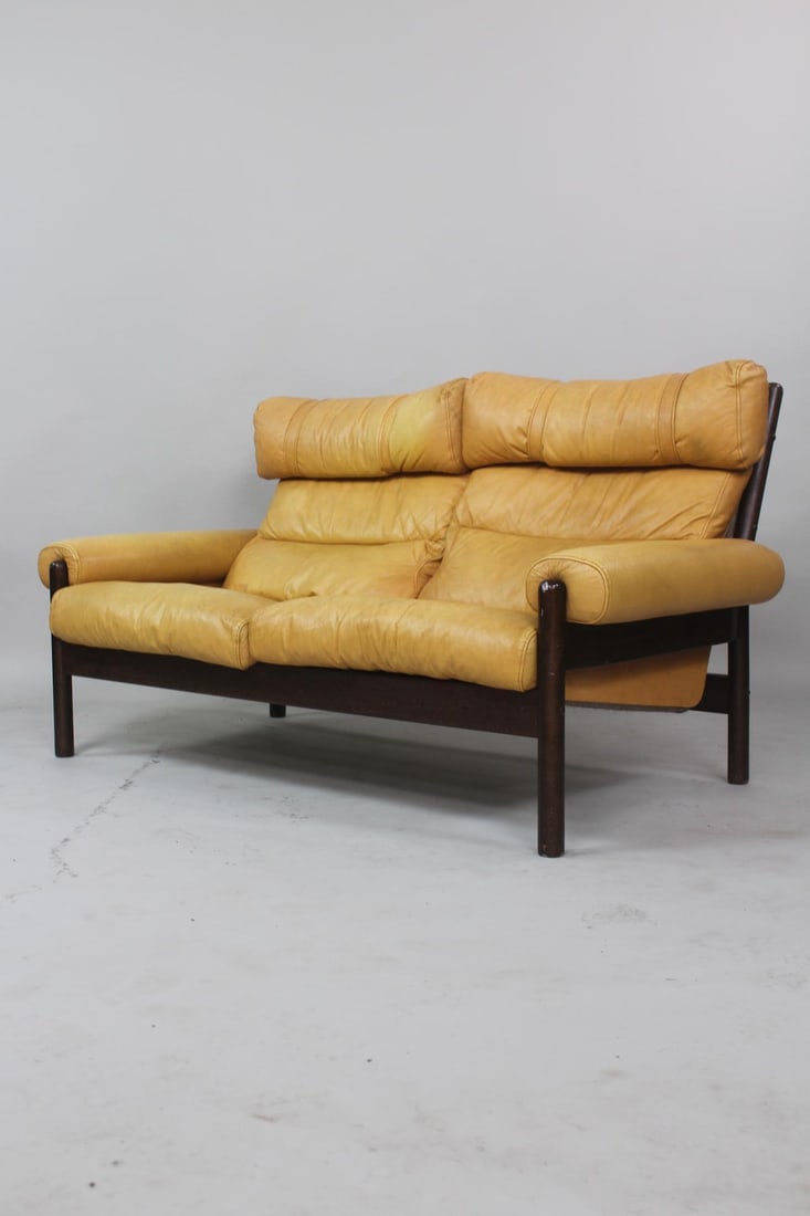 Mid-Century Modern 2-Seater Safari Sling Sofa: Vinyl & Wood Loveseat Sofa, Style of Arne Norell. This sofa features a dark wood frame with a sling-style construction for the seat and back cushions, which are upholstered in naples yellow vinyl. Unm