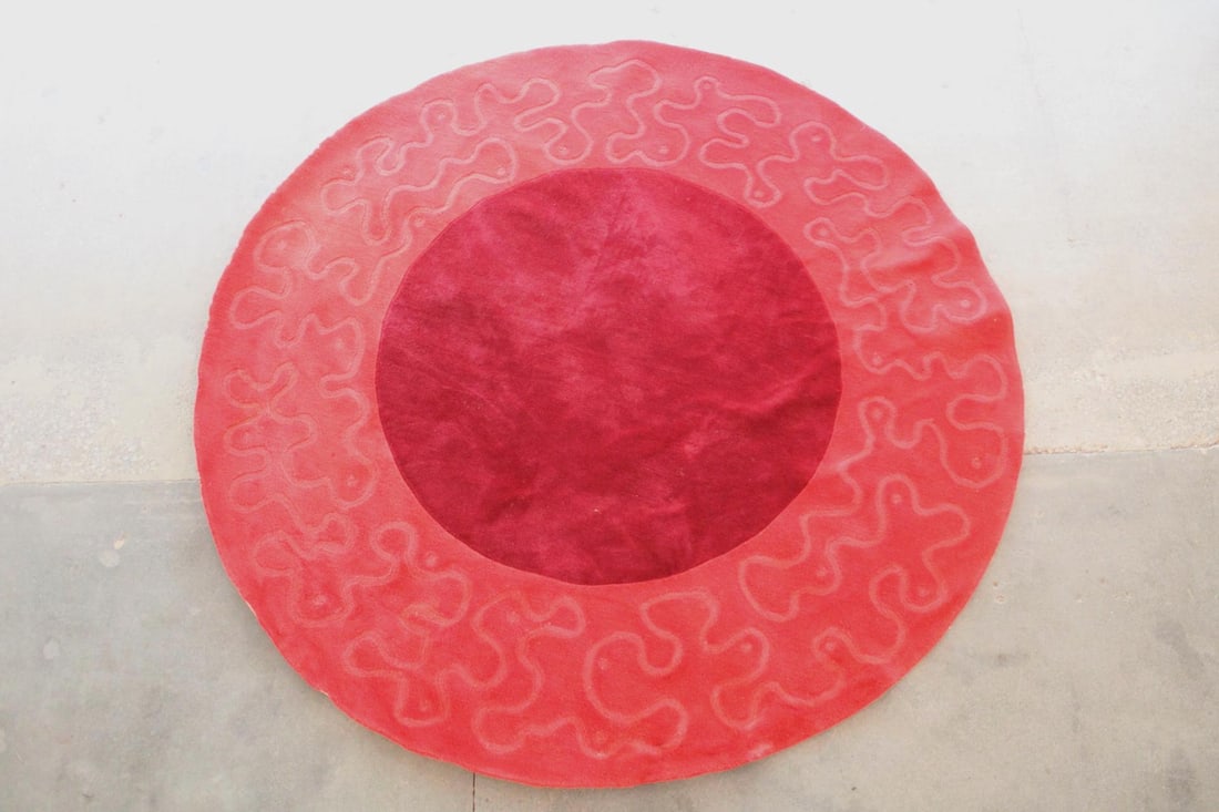 8' Circular Red Rug with Abstract Border: Mid-Century Modern Round Circle Rug. A tufted wool rug that has a solid burgundy interior and cadmium red border with abstracted squiggle design. Dimensions are 96 in h x 96 in w x .5 in d. Condition