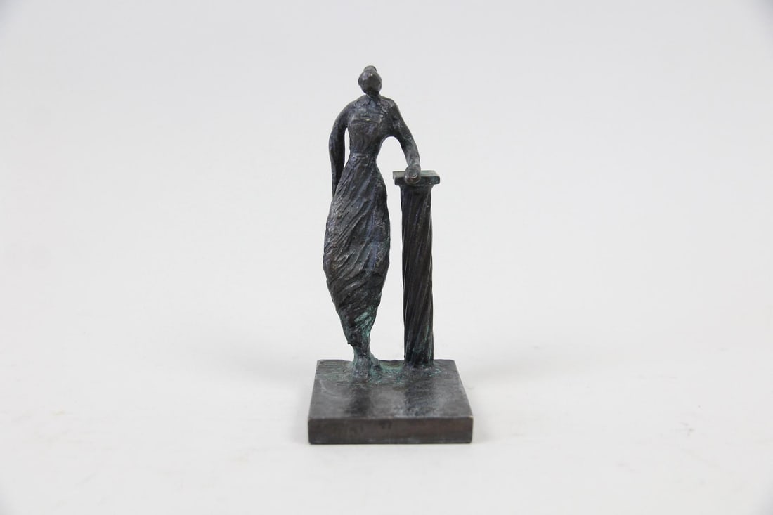 Mustafa Ali Modernist Bronze Sculpture of a Woman: Mustafa Ali Small Modernist Bronze Sculpture of a Woman. This artist work is in the style of Giacometti. Small sculpture of a woman leaning on a column, vast in bronze with a patinated finish. Inscrib