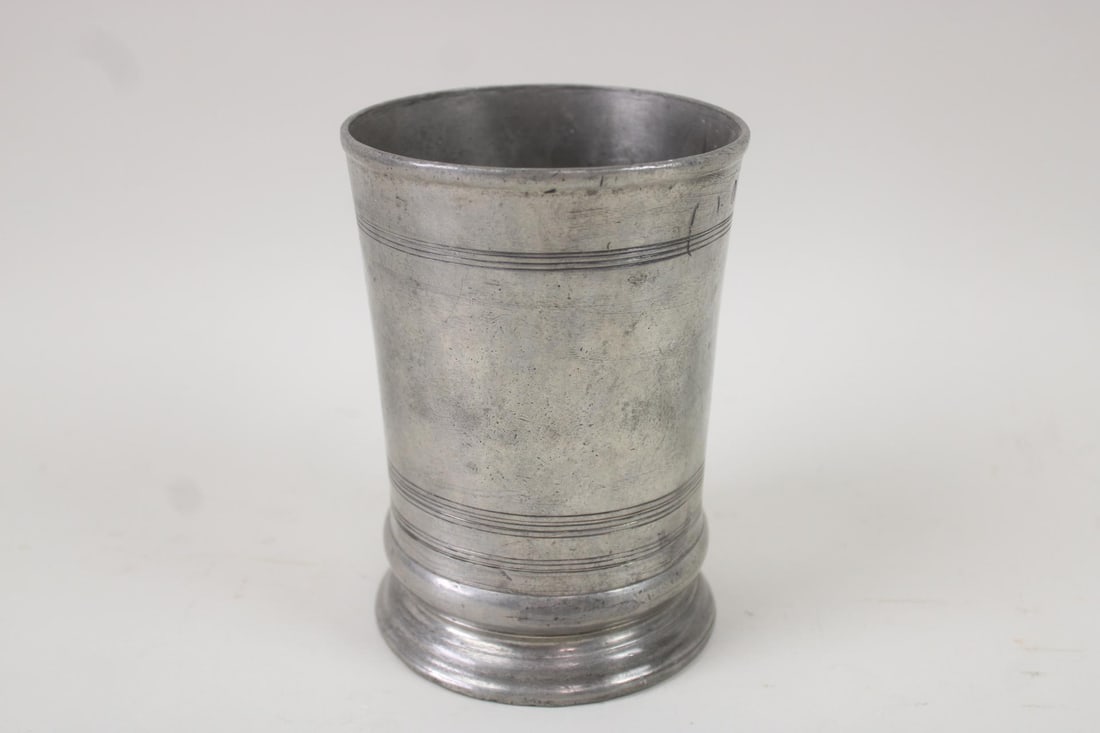 British Hallmarked Pewter Beaker Vase: Antique Hallmarked Pewter Beaker Vase. Pewter vessel with nice patina is hallmarked on the side, and indistinctly inscribed on the underside. Dimensions are 6.25 in h x 4.5 in w x 4.5 in d. Condition