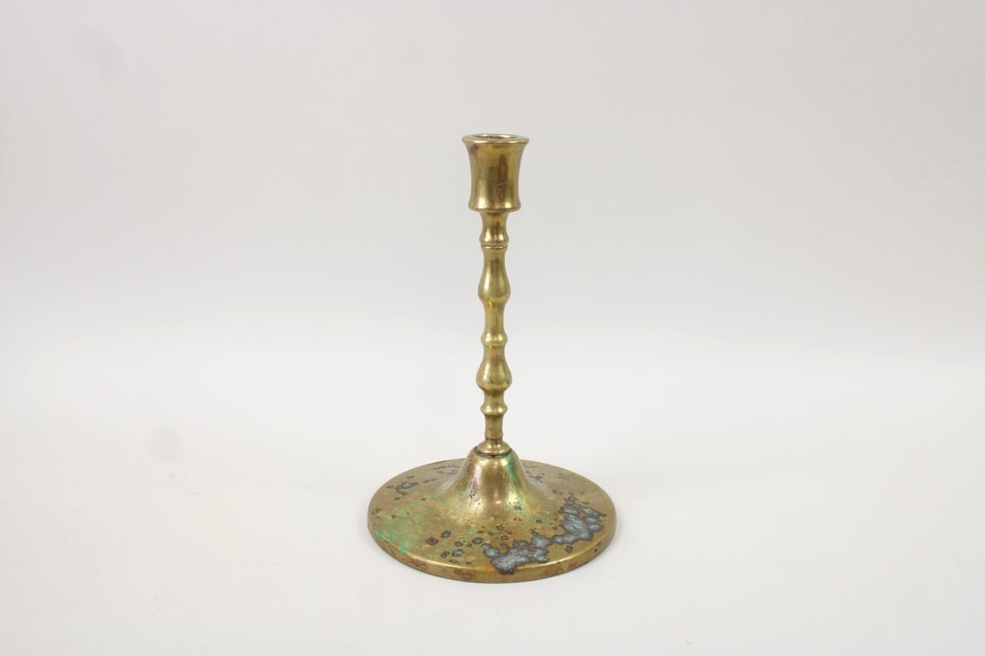 Single Brass Patinated Candle Stick: Single Brass Patinated Candle Holder. This elegant candlestick has a segmented, twisted shaft and wide round base with aged green patina. Dimensions are 11.5 in h x 7.5 in w x 7.5 in d. Condition is g