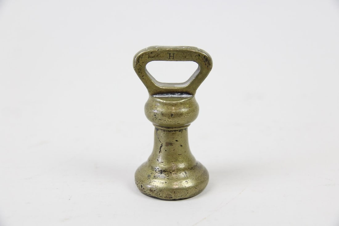 Victorian Sculptural Brass Bell Weight, Paperweight: Victorian Patinated Brass Bell Weight Scale Balance. A sculptural object with a flared, round base that tapers to a narrower stem with loop handle. Top handle is engraved H, bottom engraved ITC. Dimen