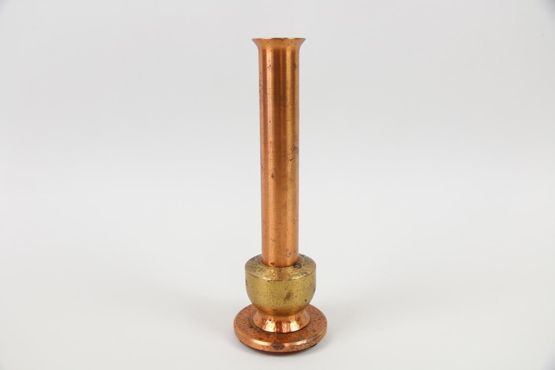Machine Age Copper Candlestick, Minimalist: Machine Age Copper Candlestick. A single, heavy candlestick with a graduated cylinder shape and tiered base. Made of textured copper and brass colored metal. Dimensions are 9 in h x 3 in w x 3 in d. C