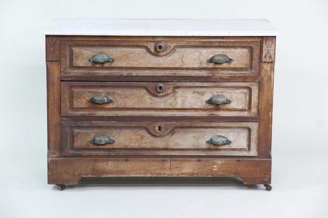 Eastlake Victorian Burl Front Dresser with Marble Top: Eastlake Victorian Burl Front Dresser with Marble Top. Three drawer dresser featuring carved wood details, brass pulls, casters and burl veneer front drawers. Dimensions are 28.5 in h x 39 in w x 17 i