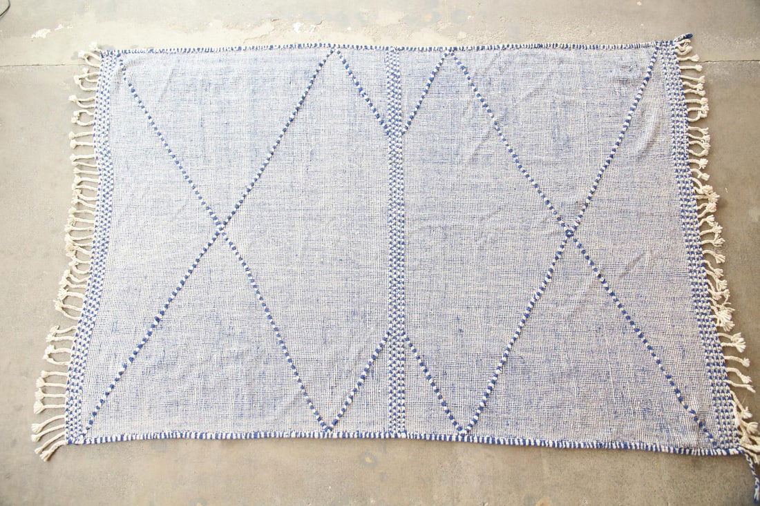 Moroccan Zanafi Berber Area Rug, Wool, 7 x 11 Ft: Moroccan Zanafi Berber Area Rug, Wool, 7 x 11 Ft. This flatweave rug has minimal diamond patterning in blue wool on an off-white foundation with braided tassels. Dimensions are 137 in l (including tas