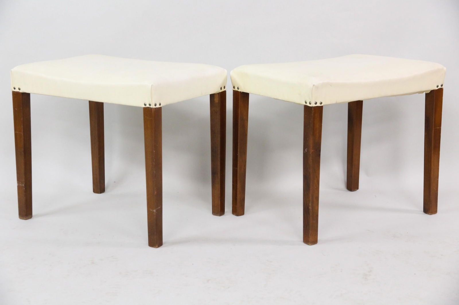 Pair of Danish Modern Footstools in Cream: Pair of Danish Mid-Century Modern, Foot stools Ottomans. Great matching pair of stools with wooden frames and cream vinyl seats. Nice details including brass studded corners.Dimensions are 16.5 in h x