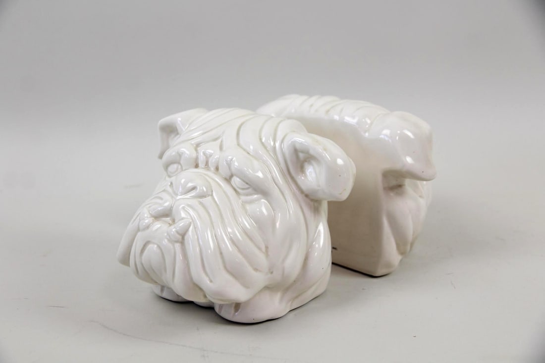 Pair of Porcelain Bulldog Bookends by Fitz & Floyd: Mid-Century Modern Pair of Porcelain Bulldog Bookends by Fitz & Floyd. Bookends with expressive bulldog faces, made of white glazed porcelain. Each stamped to back, Fitz & Floyd, MCMLXXVI (1976). Dime