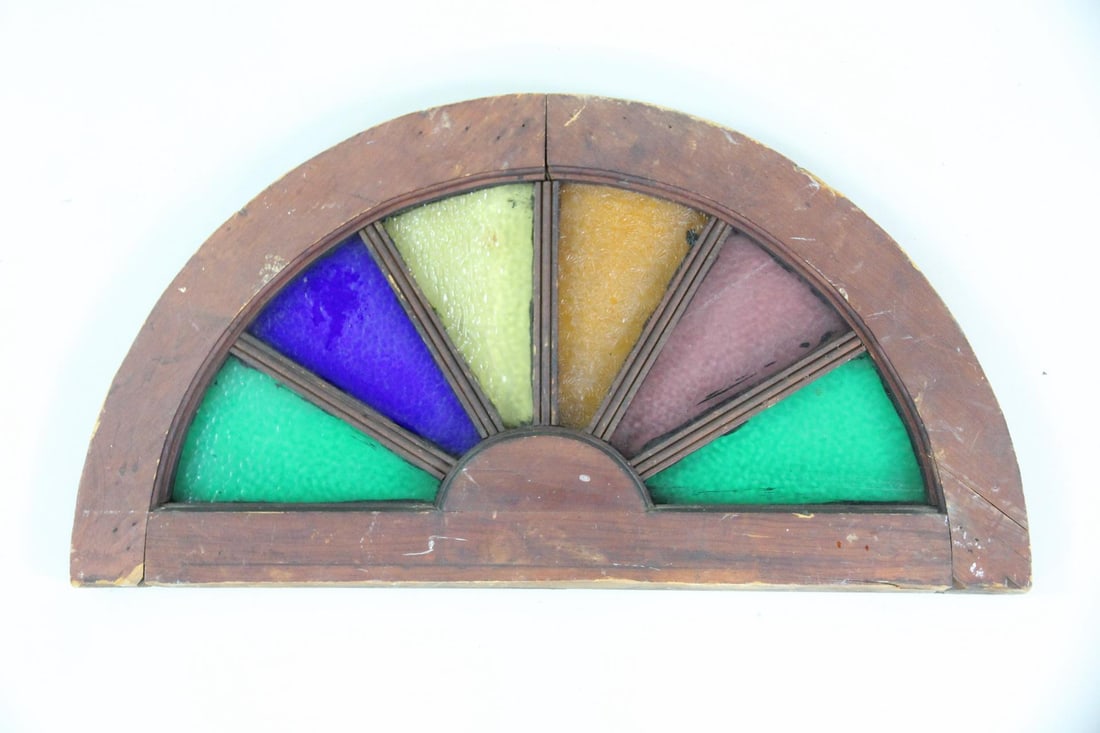 Sunburst Multicolor Stained Glass Fanlight Window: Sunburst Multicolor Stained Glass Fanlight TransomWindow. Arched demilune window is made in a sunburst pattern divided into yellow, purple, green and orange colored segments in a wooden frame. 