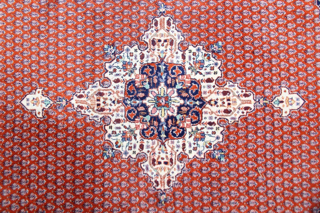 Indian Wool Rug, White Medallion & Navy Corners: Indian Wool Rug, White Medallion & Navy Corners. A Persian-style handwoven rug featuring a clear central medallion on a rust colored field with repeating motifs. Wool on cotton, with label to