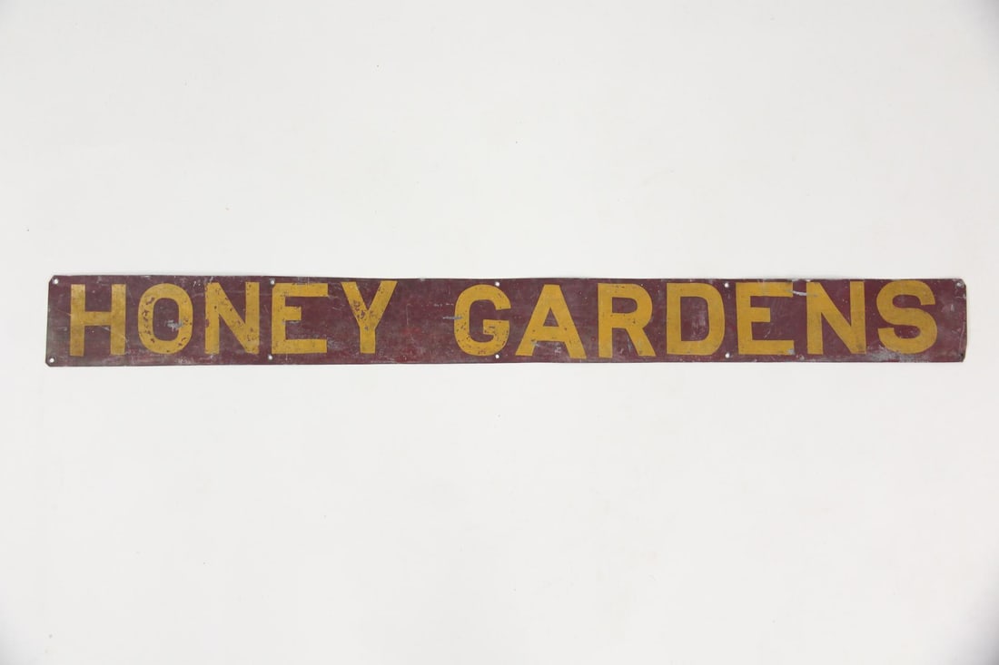 Primitive "Honey Gardens" Tin Farm Sign: Primitive "Honey Gardens" Tin Farm Sign. Tin sign with "Honey Gardens" painted in yellow letters on a maroon background. Nice patina. Dimensions are 4 in h x 42 in w x .1 in d. Condition is good with