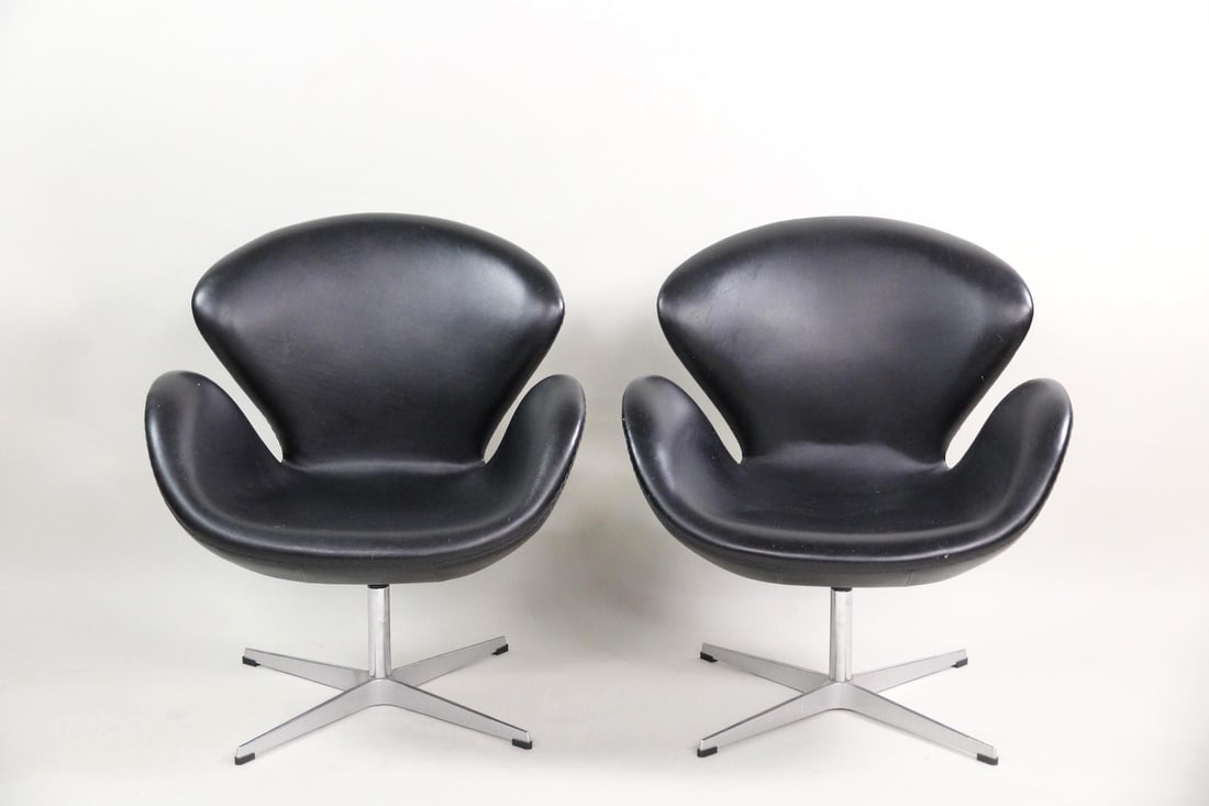 Pair of Arne Jacobsen Swan Chairs, Black Leather: Pair of Mid-century Modern Arne Jacbosen Swan Chairs, Fritz Hansen. These two space age armchairs have black leather upholstery and curved backs & arm rests, on 4-star metal bases. No maker's mark,