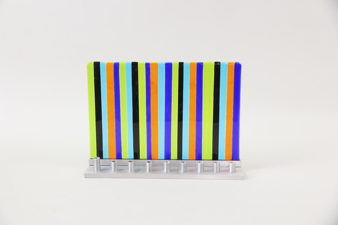 Tamara Baskin Fused Glass Menorah: Tamara Baskin Fused Glass & Metal Menorah. A menorah made of colorful fused glass in vertical stripes with brushed metal candle cups. Initialed "BSK" in marker to the underside, this piece is by the