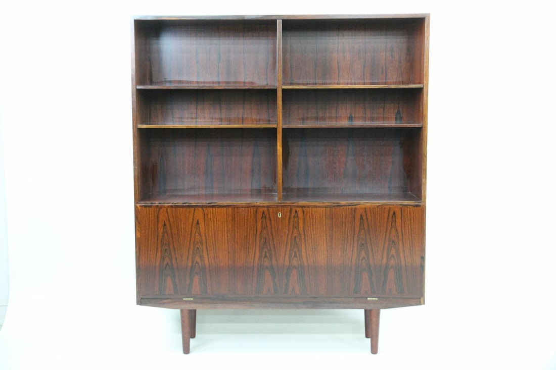 Omann Jun Rosewood Bookcase, Model 9: Danish Modern Omann Jun Rosewood Bookcase, Wall Unit, Model 9. A beautiful rosewood bookshelf with three upper shelves and bookmatched hinged door that opens to several storage compartments. Labeled O