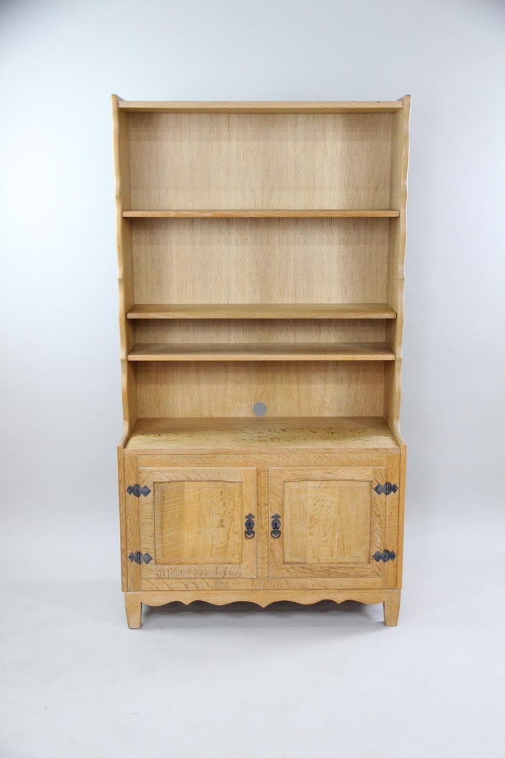 Rustic Oak Stepback Bookcase with Cabinet, Henning Kjaernulf: Danish Oak Stepback Bookcase, Manner of Henning Kjaernulf. Tall bookcase with scalloped edges, iron pulls and a 2 door cabinet on the bottom. Dimensions are 72.5 in h x 39.5 in w x 17.5 in d.