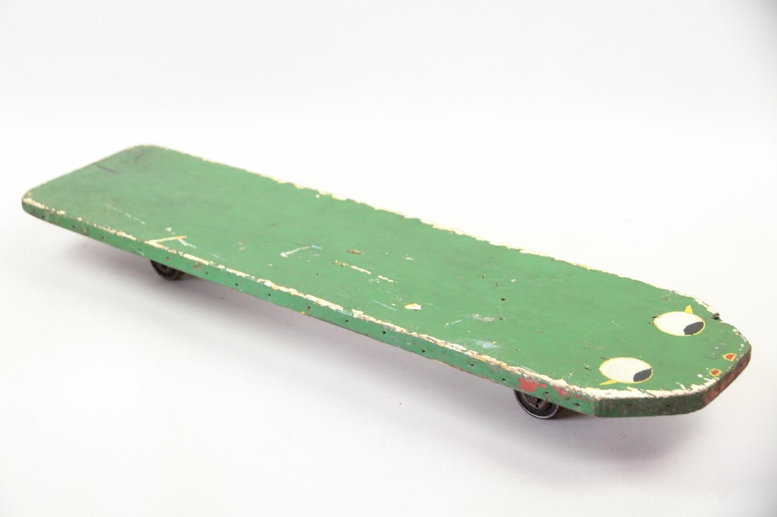 Folk Art Snake Skateboard: Folk Art Snake or Frog Skateboard. Handmade skateboard made of wood and painted green with eyes on the end. Rollerskate wheels are mounted on the underside and it's marked BOB Y. Dimensions are 3.5 in