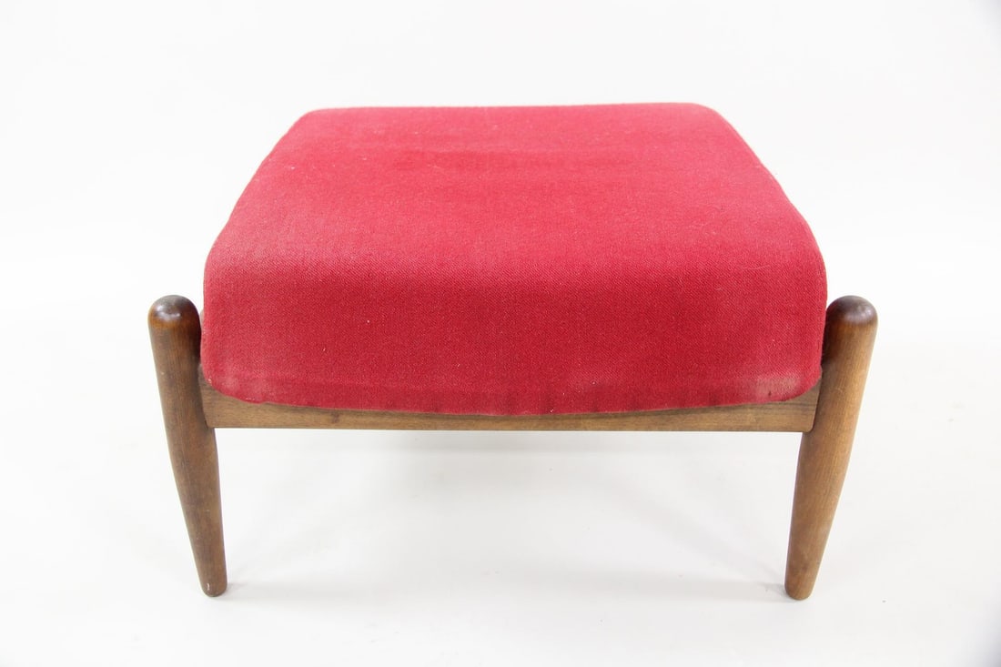 Wooden Ottoman with Red Wool Upholstery: Mid-century Modern Wooden Foot Stool with Red Wool Upholstery. An ottoman with tapered wooden legs and upholstered cushion in a scarlet red wool. Dimensions are 15.5 in h x 23 in w x 19 in d. Conditio