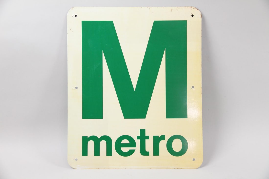 Green and White Enamel Painted Metal Metro Station Entrance Sign: Green and White Enamel Painted Metal Metro Station Entrance Sign. This vintage sign once served to mark the entrance to a city's metro system. It features a large, uppercase "M" above the word "metro"