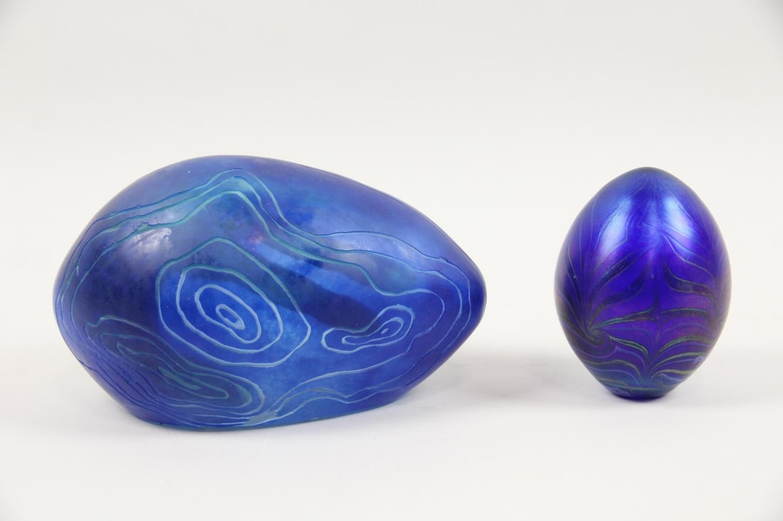 Pair of Blue Art Glass Egg Shaped Paperweights, Vandermark: Pair of Blue Art Glass Egg Shaped Paperweights. Includes an iridescent art glass egg paperweight with a blue pulled feather design signed Vandermark 1976 and the other with a design resembling topogra