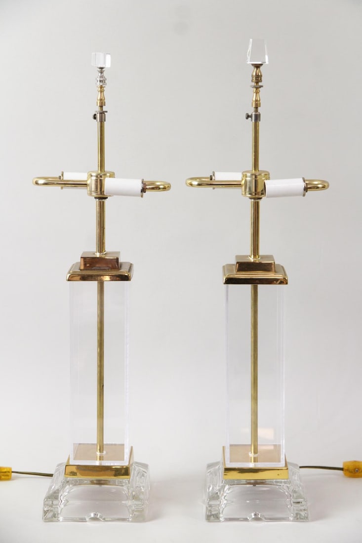 Pair of Lucite & Brass Table Lamps: Pair of Hollywood Regency Lucite & Brass Table Lamps. Matching pair of lucite, glass and brass lamps with column bases. Finials do not match. Dimensions are 24.25 in h x 7.5 in w x 5.5 in d. Condition
