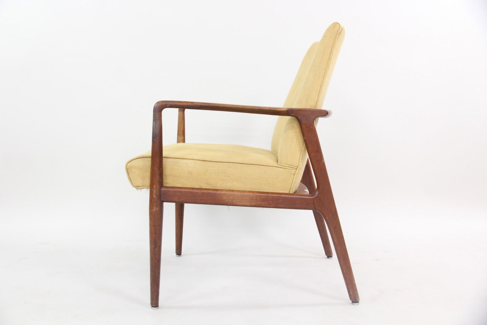 Mid-century Modern Teak Lounge Chair: Mid-century Modern Teak Lounge Chair. A teak armchair with slender frame, upholstered in light yellow fabric. Dimensions are 32.5 in h x 25.5 in w x 27 in d. Seat rise is 18 in h. Condition is fair wi