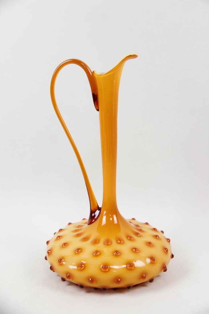 Empoli Italian Amber Cased Glass Hobnail Pitcher: Mid-Century Modern Empoli Italian Amber Cased Glass Pitcher, Vase. Tall pitcher with narrow neck and hobnail textured surface on the round body. Dimensions are 15.5 in h x 9 in w x 9 in d. Condition