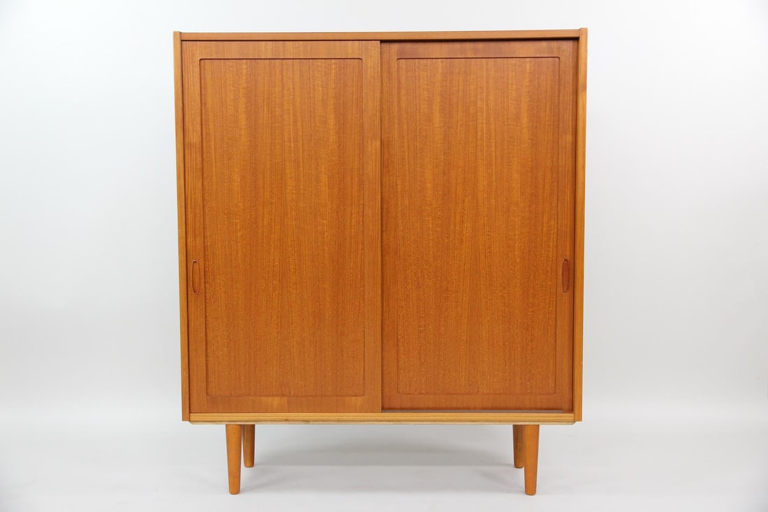 Poul Hundevad Danish Teak Cabinet: Poul Hundevad Danish Teak Cupboard. Beautiful teak sliding door cabinet with slim, sculptural pulls, tapered legs, and ample shelving inside. Labeled Hundevad, Danish Furniture Makers. Dimensions are
