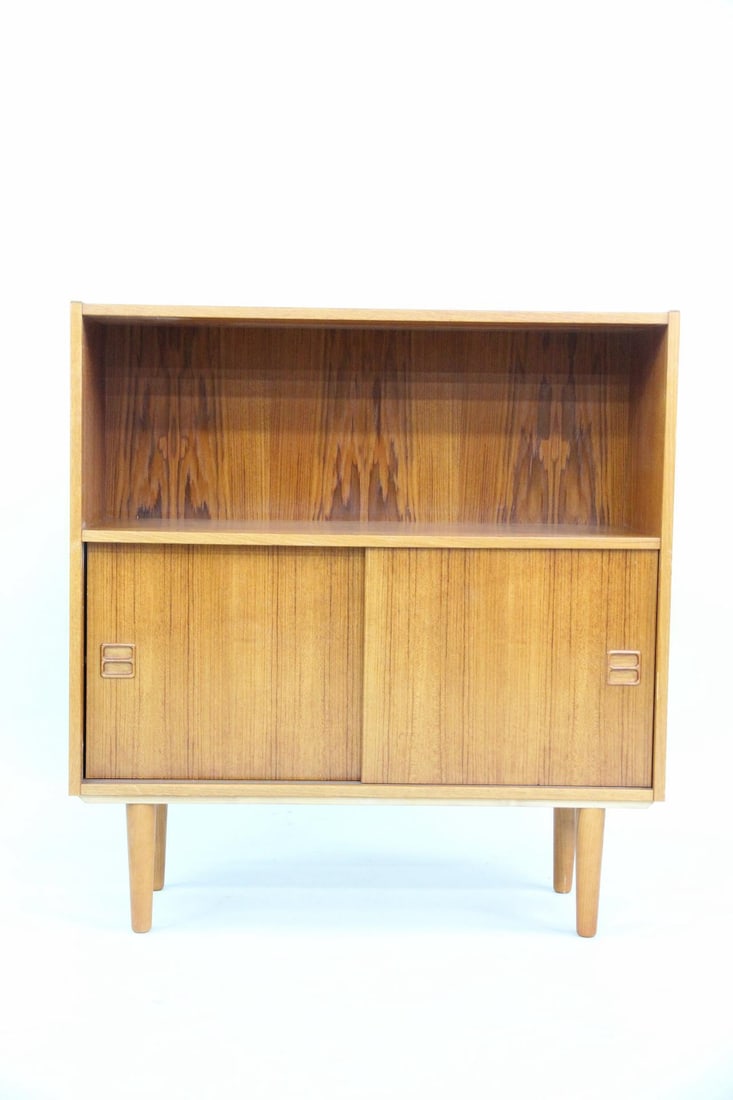 Teak Bookcase Cabinet: Danish Mid-Century Modern Teak Bookcase Cabinet. Small minimalist cabinet with bookshelf and sliding doors. Dimensions are 37 in h x 35 in w x 11.5 in d. Condition is good with some wear to top.