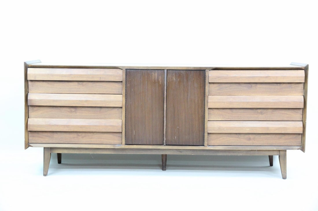 Lane "First Edition" Walnut Credenza: Mid-century Modern Lane "First Edition" walnut credenza. Credenza with distinctive ribbed center doors, beveled drawer pulls, a raised lip on the top and 9 drawers. Unmarked. Dimensions are 32 in h x