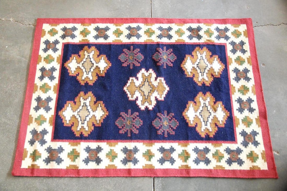 Geometric Kilim Wool Rug, Navy, Cream, & Coral: Geometric Kilim Wool Rug, Navy, Cream, & Coral. A flatweave wool rug featuring a deep navy center field with bold geometric medallions and smaller patterned motifs within a cream border. Dimensions