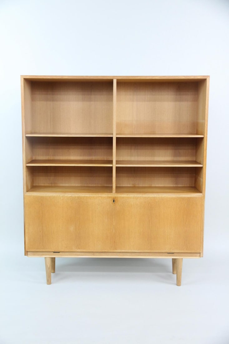 Omann Jun Oak Bookcase Wall Unit Model 9: Danish Modern Omann Jun Oak Bookcase, Wall Unit, Model 9. A beautiful light oak bookshelf with three upper shelves and book matched hinged door that opens to several storage compartments. Labeled Oman