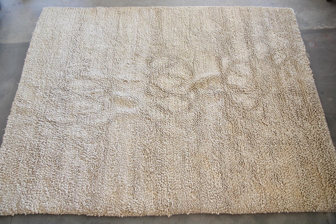 Minimalist Shag Wool Area Rug, Cream, 9 x 11 Ft: Minimalist Shag Wool Rug, Cream, 9 x 11 Ft. This rug has a thick, shag pile made of cream-colored wool. Dimensions are 137 in l x 105 in w x 1.25 in d. Condition is good with some wear and discolorati