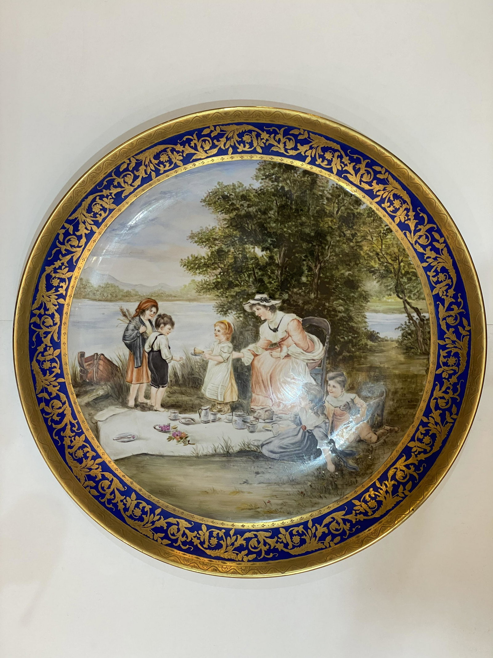 Royal Vienna Large Porcelain Decorative Plate: Large Porcelain Decorative Plate with Gold Leaf. Hand painted scene of a family having a picnic by the lake. Marked Royal Vienna, possibly attributed to Ackermann & Fritz (Volkstedt, Germany, ca 1908-