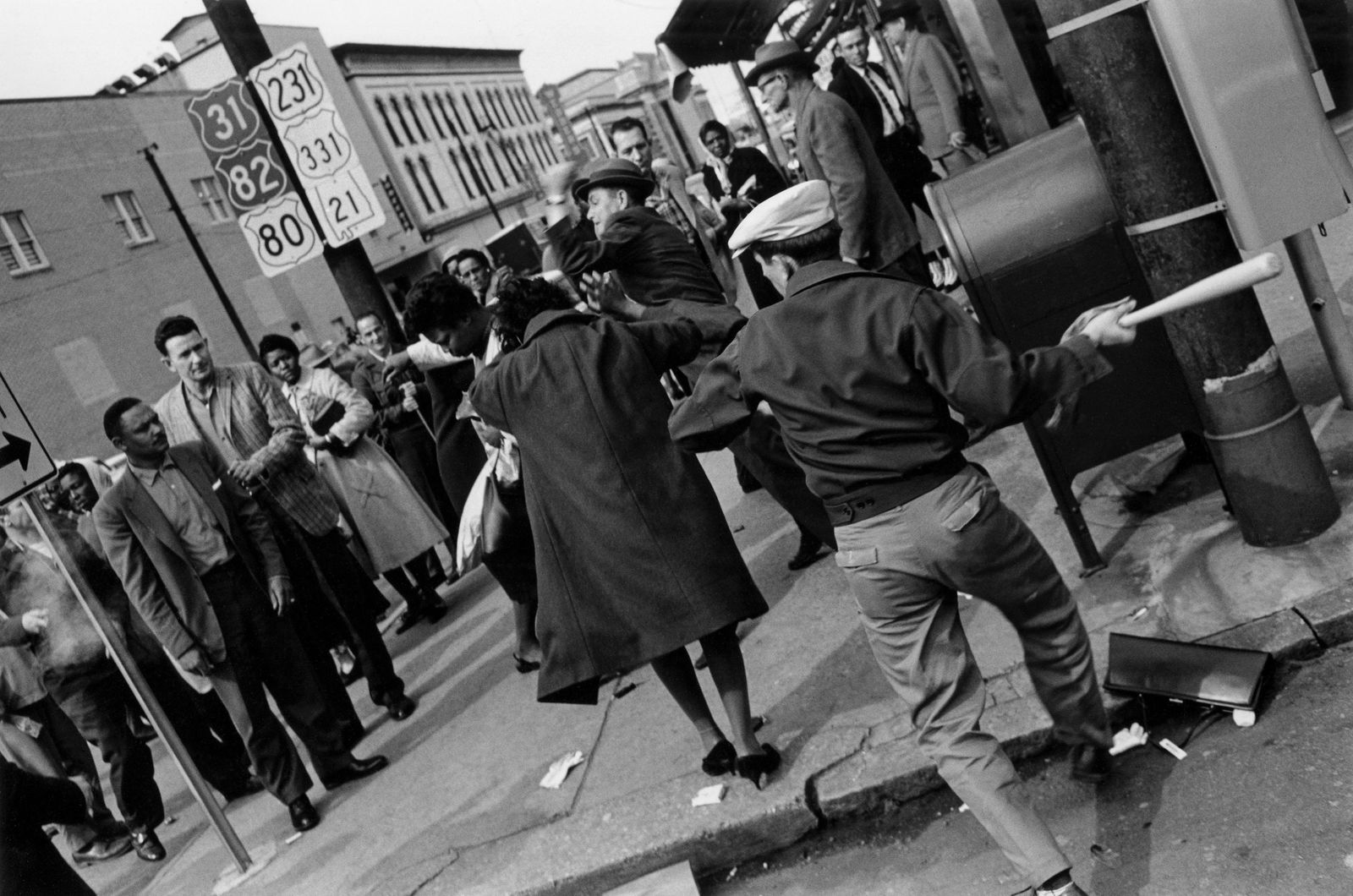 CHARLES MOORE A White Man Swings a baseball bat, 1960: CHARLES MOORE (1931-2010) A WHITE MAN SWINGS A BASEBALL BAT AT A SHOPPER, WHILE ANOTHER STRIKES A BLACK WOMAN IN THE BACKGROUND. THE ATTACK IN 1960 OCCURRED THE DAY AFTER BLACK STUDENTS WERE REFUSED S
