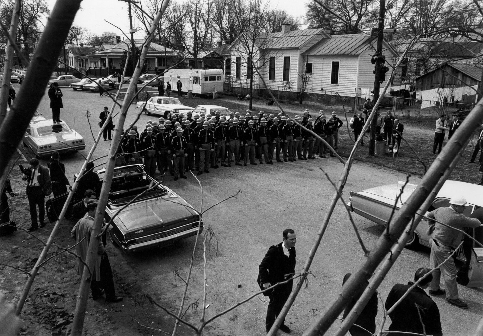 CHARLES MOORE State Police wait for the Marchers, 1965: CHARLES MOORE (1931-2010) STATE POLICE WAIT FOR THE MARCHERS, 1965 gelatin silver print, printed later; 9 1/16 x 13 in. (image), 11 x 14 in (sheet); signed verso in pencil; Condition: Excellent: EG# C