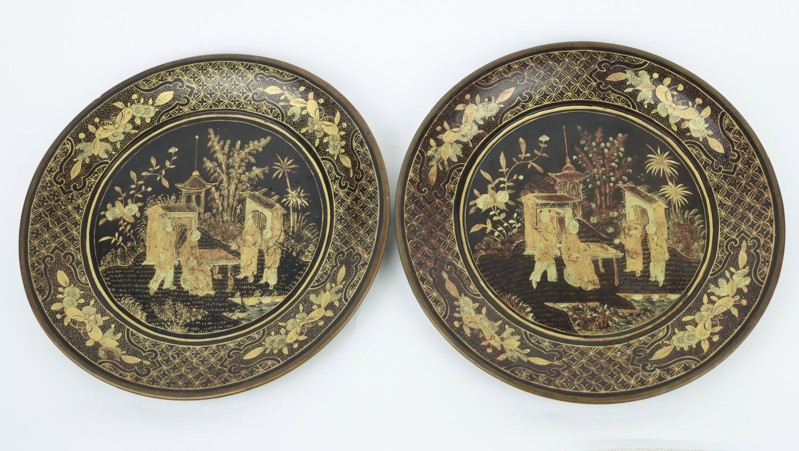 A Pair of 19th Century Chinese Export Gilt Lacquered Wood Plates: A Pair of 19th Century Chinese Export Gilt Lacquered Wood Plates nicely decorated in the Chinese Export style featuring patterns of coins, flora and moths bordering a centeral painted scene of aristoc