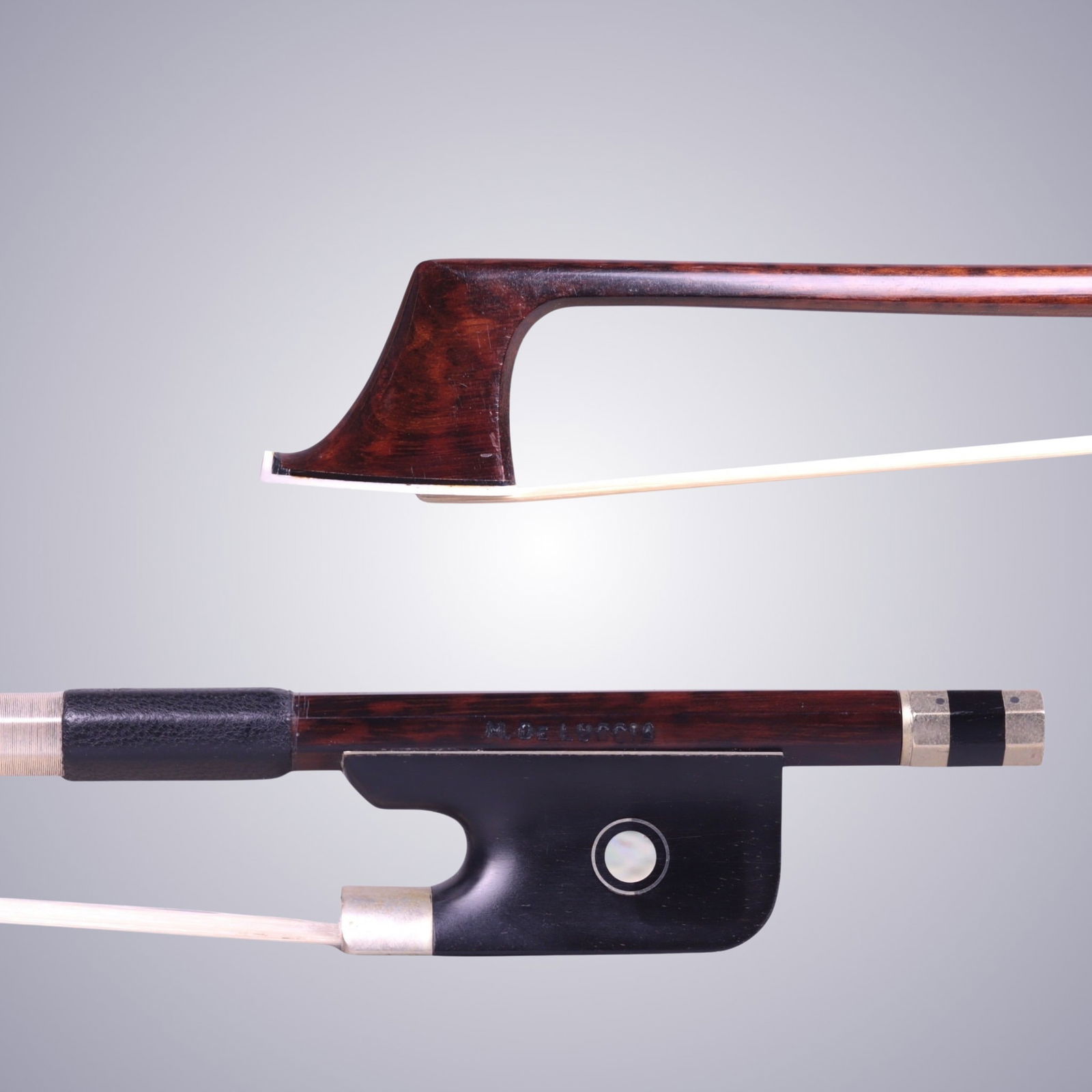 A CELLO BOW STAMPED M. DELUCCIA: A CELLO BOW STAMPED M. DELUCCIA Of Round Snakewood Stick, Ebony & Nickel mounted. Stamped on stick above frog: M. DELUCCIA Approximate Dimensions: 71.5 cm (Total Length - Head to Adjustor) 82.8 Grams