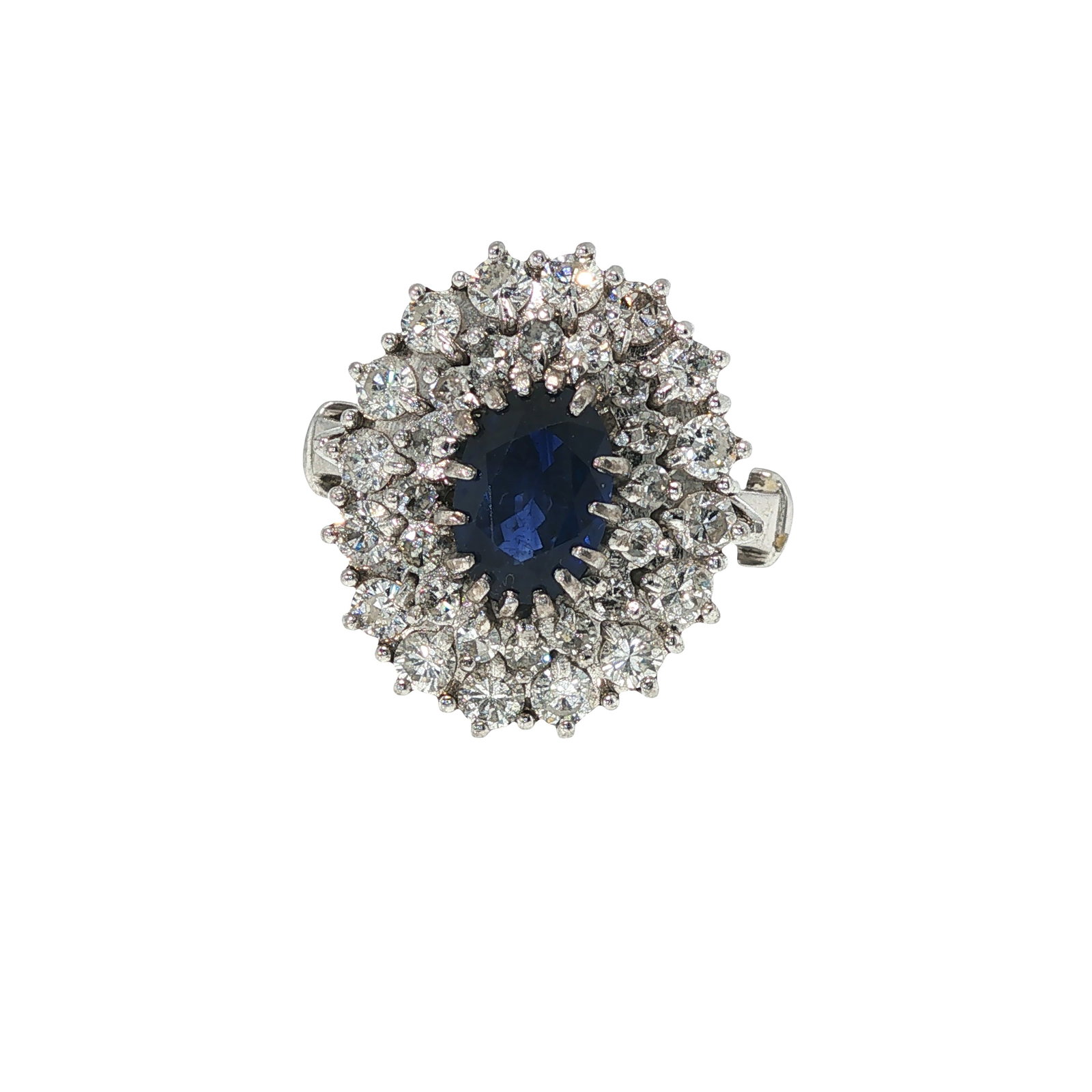 14K WHITE GOLD SAPPHIRE AND DIAMOND RING: 14K WHITE GOLD SAPPHIRE AND DIAMOND RING A 14K white gold ring centered by an oval faceted sapphire, surrounded by a tiered cluster of round brilliant-cut diamonds. The elevated setting creates a