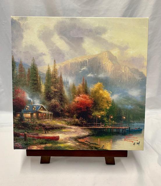 Thomas Kinkade Accent Print with Easel COA: Thomas Kinkade Accent Print with Easel COA. Cabin, Canoe, Lake, Mountains. Apx 14" W x 14" T. COA. With Table Top Easel.