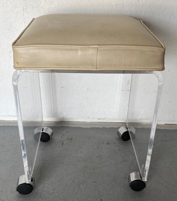 Lucite Vanity Rolling Seat: Lucite Vanity Rolling Seat. Vinyl Seat with a few pokes. On Castors. Apx. 12 1/2" x 14" x 19" H. Photos are considered part of the description and condition.