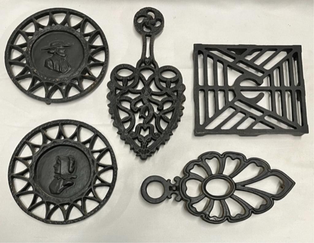 5 Assorted Wrought Iron Trivets: 5 Assorted wrought Iron Trivets. -Pair of 6 1/2" round Amish man and woman. #293. -9" Iron. -7" x 6" Grate with C Initial in center. #6644. -Iron Trivet. Marked J.Z.H. 1948. Photos are considered part