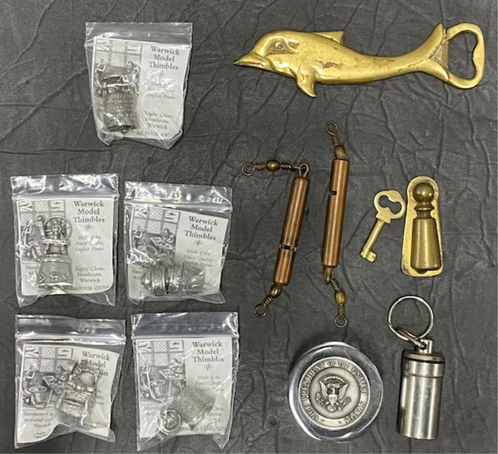 Assortment of Thimbles and other trinkets: Assortment of Thimbles and other trinkets.5-Warwick Model Thimbles.1-Vice President of the Unites States Paper Weight.2-Brass Whistles.1-Metal Storage Keychain.1-Brass Dolphin Bottle Opener.1Brass Key