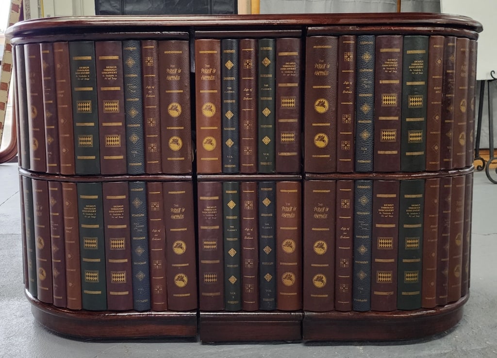 Unique Faux Book Game Table w/ (2) Chairs: Faux book oblong shaped game table with (2) rolling chairs complete with game pieces. Top has some worn spots and rim of chair has wear marks. Approx. 30" height, 50" width, and 24" depth. Photos are