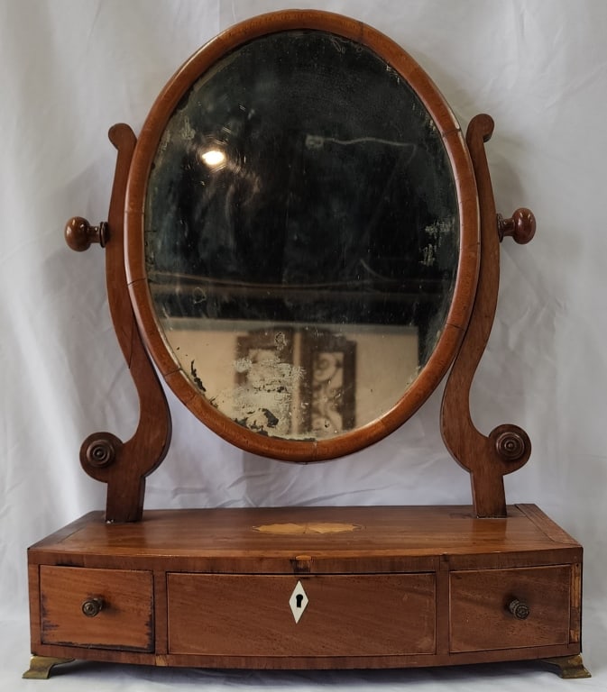 Antique Edwardian Style Inlaid Shaving Mirror: Antique Edwardian style inlaid shaving mirror. Featuring 3 drawers and brass feet. Small piece of veneer missing from bottom right. Mirror has age spots present. Approximately 22.5"h x 17.5"w x 8"d. P