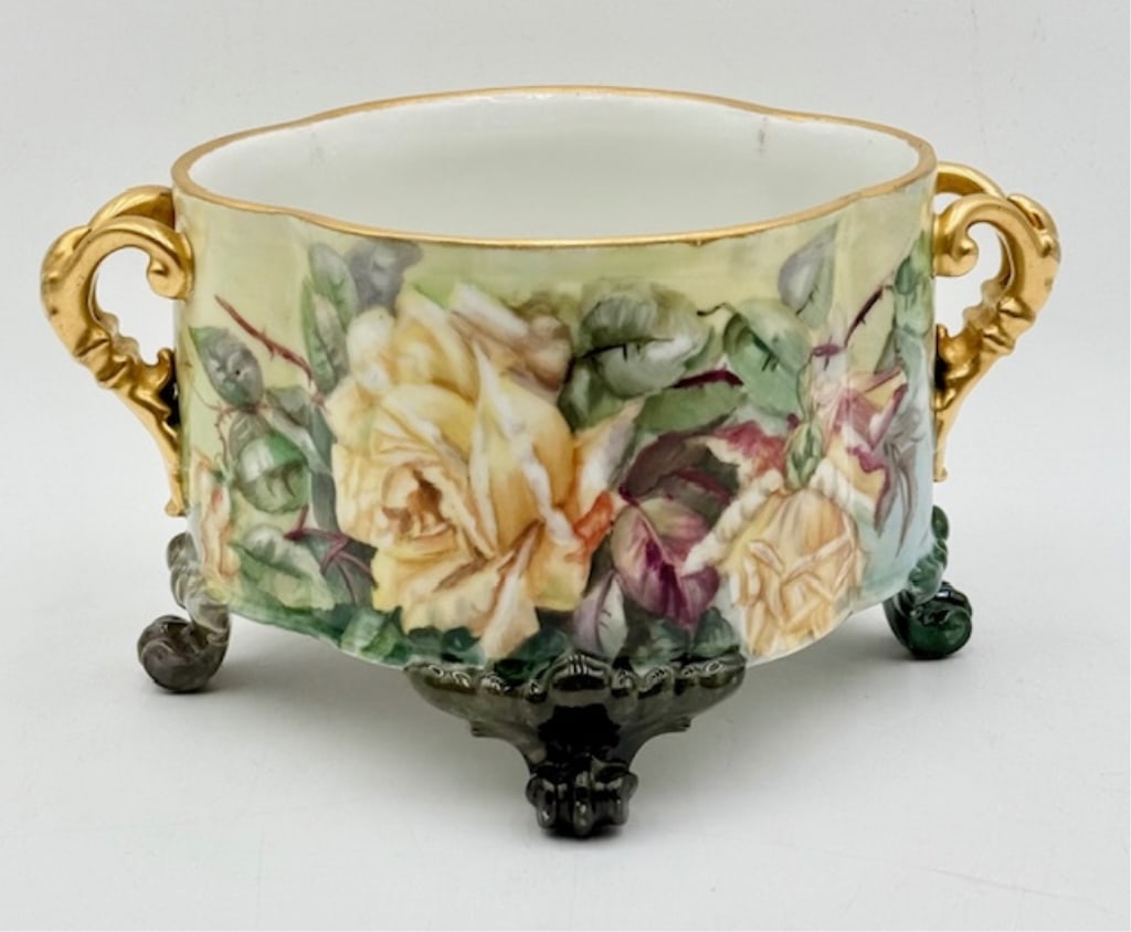 Antique Hand Painted & Signed Footed Jardiniere: Antique hand painted and signed footed jardiniere. Double gold handles. Some minor wear to gold. Beautiful roses motif. Signed 1904. Approximately 6"h x 10.75"w x 9"d. Photos are considered part of th