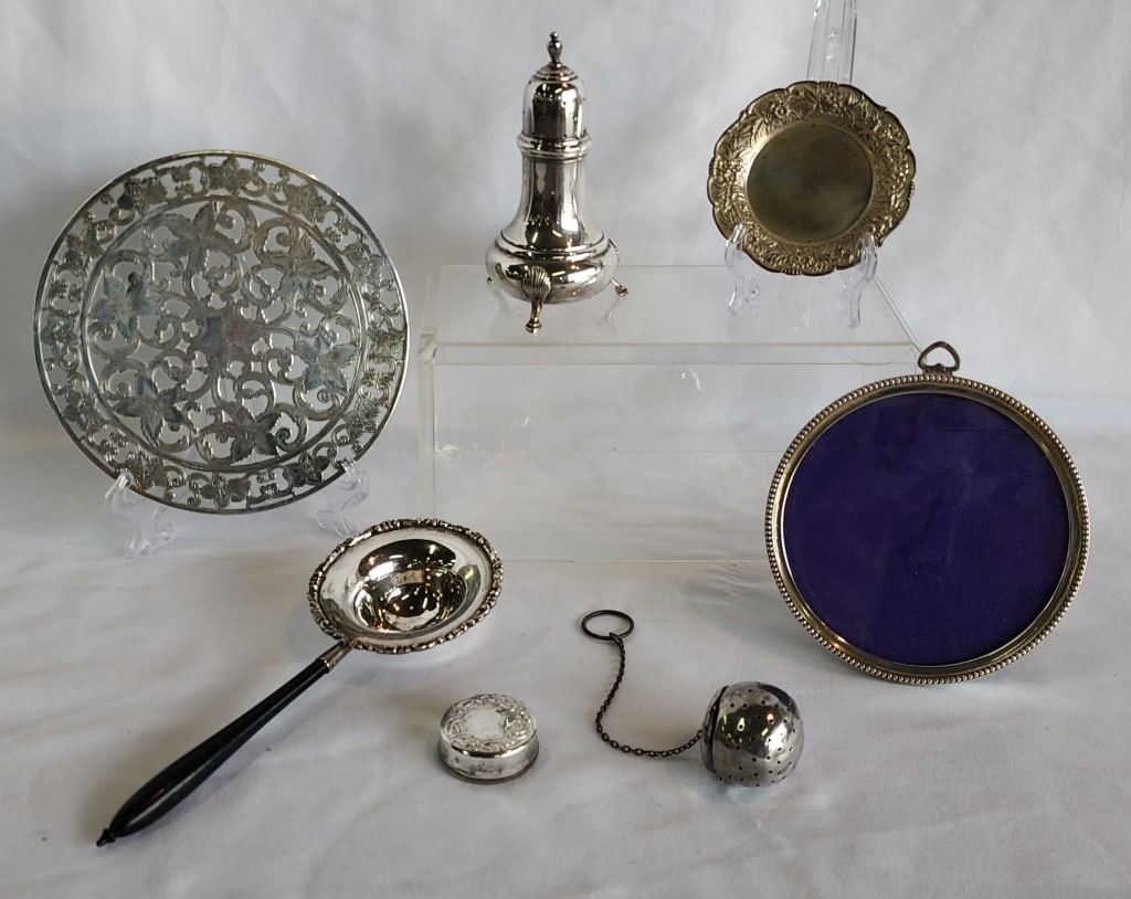 Assorted Sterling Silver Items: Assorted sterling silver items. Includes 4.5" round picture frame, 1.25" pill box, 6" round glass sterling overlay trivet, 3.5"d round trinket, 4.5" salt shaker, 7.25" tea strainer, and tea ball. Phot