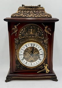 Tempus Fugit Wooden Mantle Clock: Tempus Fugit wooden mantle clock. Featuring attached cherub reliefs and bronze looking accents. Front glass door hinge needs to be repaired. Winds and chimes. Includes key. Approximately 15.5"h x 11.5