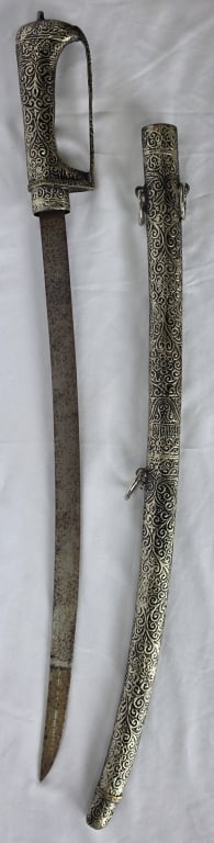 Tulwar Indian Ceremonial Sword: Tulwar Indian ceremonial sword. Heavily decorated handle and scabbard with ornate engraved pattern. Etched symbols near the hilt. Rust present on blade. Approximately 32" long. Photos are considered p