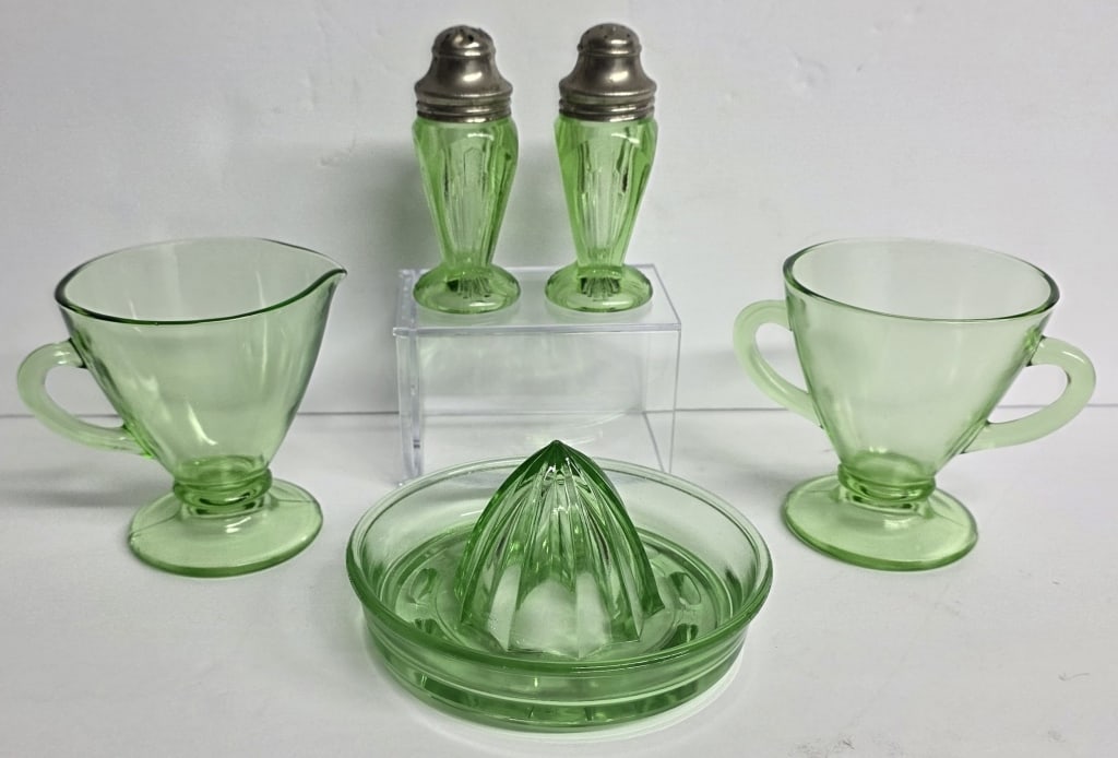 Vintage Green Uranium Glass Serveware: Collection of vintage green uranium glass serveware. Includes 3.5" creamer and sugar, 4" Hazel Atlas salt and pepper shakers, and 3" x 5" juicer. Hole present in one shaker lid. Photos are considered